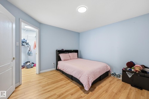Bedroom featuring wood-finish flooring, light blue wall paint, and a built-in closet with shelving - 33 9914 80 Avenue, Edmonton, AB - Indoor Photo Showing Bedroom