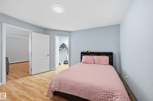Bedroom featuring light wood-finish flooring, light blue wall paint, white trim, and a ceiling-mounted light fixture - 33 9914 80 Avenue, Edmonton, AB - Indoor Photo Showing Bedroom