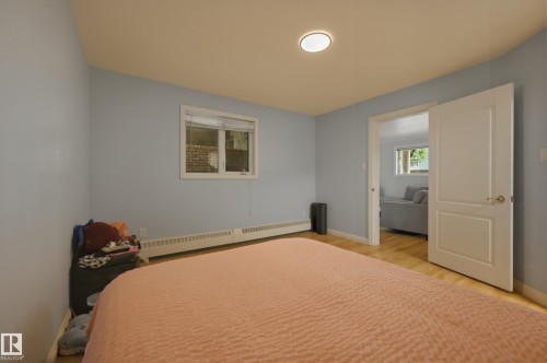 Room featuring light blue walls, wood-finish flooring, and a white trim window - 33 9914 80 Avenue, Edmonton, AB - Indoor Photo Showing Bedroom