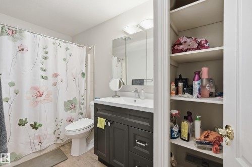 Bathroom featuring a dark vanity with a white countertop, an integrated sink, and chrome fixtures - 33 9914 80 Avenue, Edmonton, AB - Indoor Photo Showing Bathroom