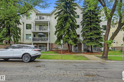 Multi-story residential building featuring multiple balconies, a covered entrance, and mature trees surrounding the property - 33 9914 80 Avenue, Edmonton, AB - Outdoor