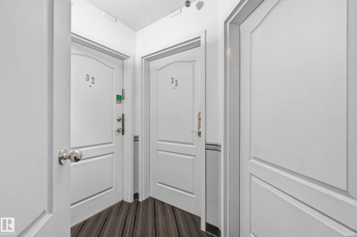 Corridor featuring wood-finish flooring and multiple white paneled doors - 33 9914 80 Avenue, Edmonton, AB - Indoor Photo Showing Other Room