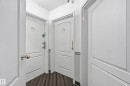 Corridor featuring wood-finish flooring and multiple white paneled doors - 33 9914 80 Avenue, Edmonton, AB  - Indoor Photo Showing Other Room 