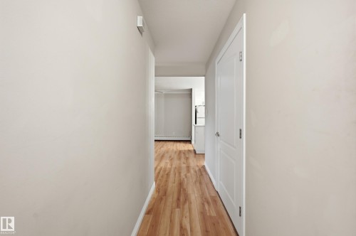 Hallway with wood-finish flooring, light-colored walls, white trim, and a white interior door - 33 9914 80 Avenue, Edmonton, AB - Indoor Photo Showing Other Room