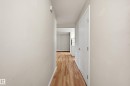 Hallway with wood-finish flooring, light-colored walls, white trim, and a white interior door - 33 9914 80 Avenue, Edmonton, AB  - Indoor Photo Showing Other Room 