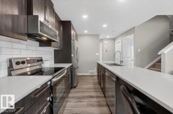 Contemporary kitchen with dark wood-finish cabinetry, stainless steel appliances, white subway tile backsplash, and light-toned countertops - 