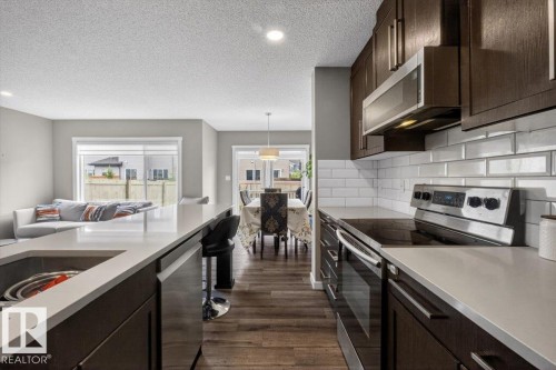 Kitchen featuring wood-finish cabinetry, stainless steel appliances, and light-toned countertops - 223 40A Avenue, Edmonton, AB - Indoor Photo Showing Kitchen With Upgraded Kitchen