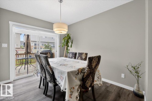Dining area featuring wood-finish flooring, a contemporary drum pendant light, and sliding glass doors leading to an outdoor deck - 223 40A Avenue, Edmonton, AB - Indoor Photo Showing Dining Room