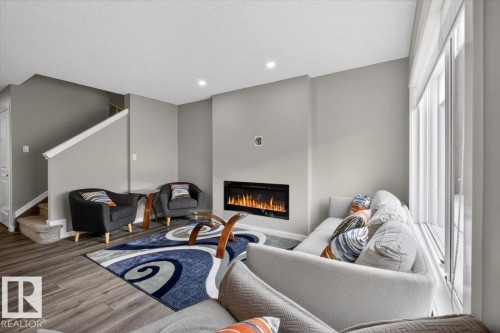 Living area featuring an integrated linear fireplace, large window with vertical blinds, recessed lighting, and wood-finish flooring - 223 40A Avenue, Edmonton, AB - Indoor With Fireplace