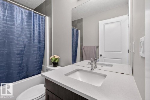 Bathroom featuring a vanity with a white countertop and integrated sink, chrome faucet, and dark wood-finish cabinetry - 223 40A Avenue, Edmonton, AB - Indoor Photo Showing Bathroom