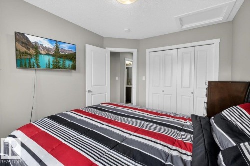 Recessed lighting illuminates this bedroom featuring a built-in closet with bi-fold doors, a mounted television, and a neutral wall palette - 223 40A Avenue, Edmonton, AB - Indoor Photo Showing Bedroom