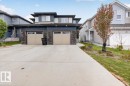 Contemporary exterior featuring dark siding, stone accents, and two light-colored garage doors - 223 40A Avenue, Edmonton, AB  - Outdoor With Facade 