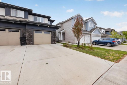 Modern townhouse with a stone and siding exterior, featuring two attached garages with frosted window panels and individual driveways - 223 40A Avenue, Edmonton, AB - Outdoor With Facade