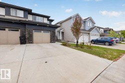 Modern townhouse with a stone and siding exterior, featuring two attached garages with frosted window panels and individual driveways - 