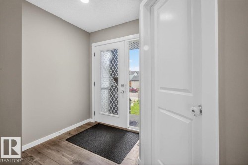 Foyer featuring a white entry door with decorative glass inserts, wood-finish flooring, and neutral wall paint - 223 40A Avenue, Edmonton, AB - Indoor Photo Showing Other Room