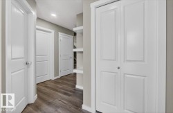 Hallway featuring wood-finish flooring, recessed lighting, white panel doors, and built-in shelving - 