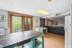 Recreation room featuring dual glass-paneled patio doors with wood trim, cork-finish flooring, and a drop ceiling with recessed lighting - 