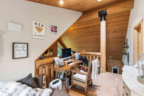 Loft area featuring sloped wood-paneled ceilings, a prominent wood column, and wood-finish flooring - #17 A 15031 Twp Road 462, Rural Wetaskiwin County, AB - Indoor