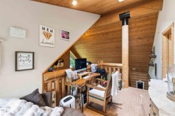 Loft area featuring sloped wood-paneled ceilings, a prominent wood column, and wood-finish flooring - 