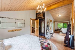 Sloped wood-paneled ceiling with exposed wood beam, chandelier lighting fixture, and light wood-finish flooring - 