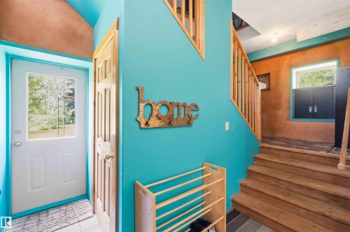 Entryway featuring a paneled door with a window, tile flooring, and a natural wood staircase with balusters - #17 A 15031 Twp Road 462, Rural Wetaskiwin County, AB - Outdoor With Deck Patio Veranda With Exterior