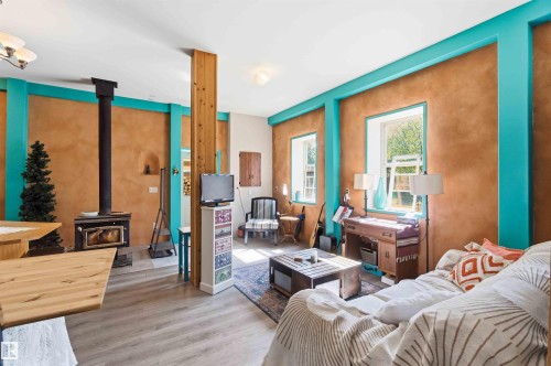Spacious interior featuring wood-finish flooring, a prominent wood-burning stove with a black flue, and exposed structural wood beams - #17 A 15031 Twp Road 462, Rural Wetaskiwin County, AB - Indoor Photo Showing Bedroom