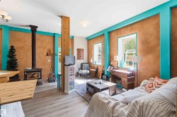 Spacious interior featuring wood-finish flooring, a prominent wood-burning stove with a black flue, and exposed structural wood beams - 
