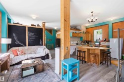 Open-concept living space featuring wood-finish flooring, exposed wood beams, and a combination of turquoise and terracotta wall finishes - 