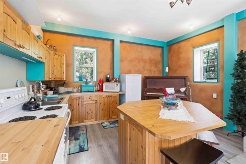 Kitchen space featuring light wood cabinetry, a double basin stainless steel sink, and a white electric range - #17 A 15031 Twp Road 462, Rural Wetaskiwin County, AB - Indoor Photo Showing Kitchen With Double Sink