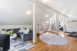 Spacious loft area featuring vaulted ceilings, exposed beams, and light wood-finish flooring - 