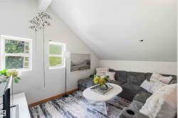 Attic living space featuring dual windows, vaulted ceilings, and wood-finish flooring - 