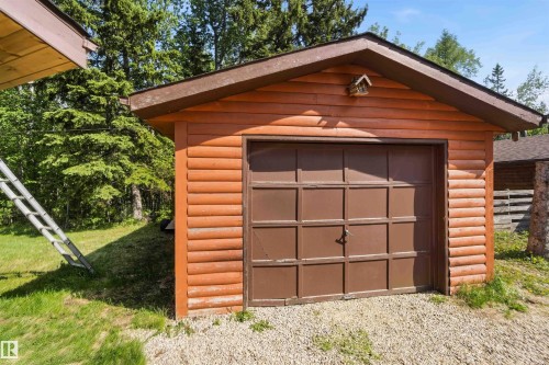 Detached outbuilding with wood-sided exterior, peaked brown roof, and a panel garage door - #17 A 15031 Twp Road 462, Rural Wetaskiwin County, AB - Outdoor With Exterior