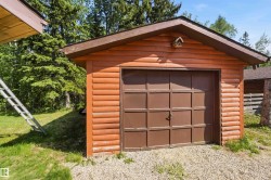 Detached outbuilding with wood-sided exterior, peaked brown roof, and a panel garage door - 