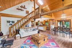 Expansive great room featuring vaulted wood-finish ceilings, an open-concept layout, and a prominent wood staircase leading to an upper-level loft - 