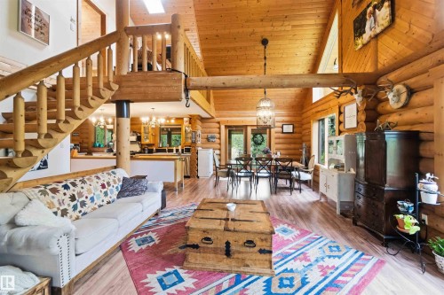 Spacious great room featuring vaulted wood-paneled ceilings, exposed log beam construction, and wood-finish flooring - #17 A 15031 Twp Road 462, Rural Wetaskiwin County, AB - Indoor Photo Showing Living Room
