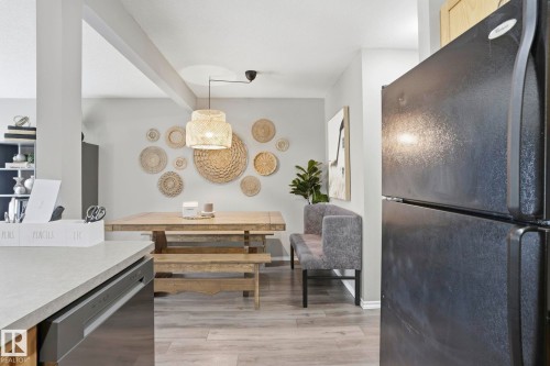 Dining area featuring light wood-finish flooring, a contemporary light fixture, and a built-in bench seating arrangement - 164 150 Edwards Drive, Edmonton, AB - Indoor