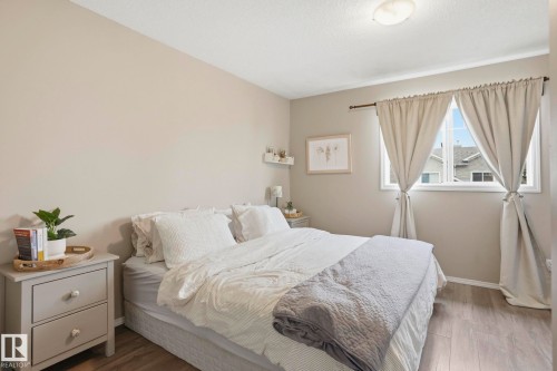 Neutral-toned bedroom featuring wood-finish flooring, a single window with curtain rods, and a ceiling-mounted light fixture - 164 150 Edwards Drive, Edmonton, AB - Indoor Photo Showing Bedroom
