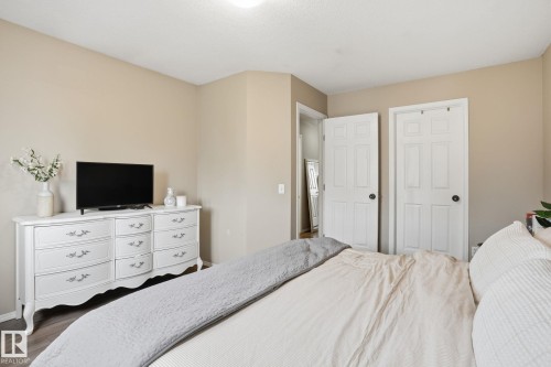 Neutral wall paint with trim, wood-finish flooring, and white interior doors - 164 150 Edwards Drive, Edmonton, AB - Indoor Photo Showing Bedroom