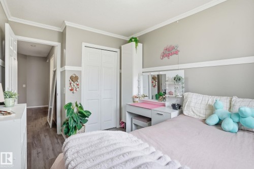 Bedroom featuring wood-finish flooring, neutral wall paint, white crown molding, and a paneled bifold closet door - 164 150 Edwards Drive, Edmonton, AB - Indoor Photo Showing Bedroom