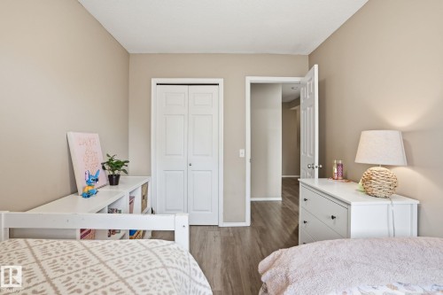 Interior room featuring neutral wall paint, wood-finish flooring, a bi-fold closet door, and a white interior door - 164 150 Edwards Drive, Edmonton, AB - Indoor Photo Showing Bedroom