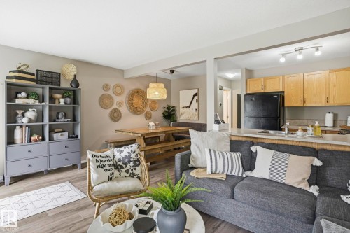 Open-concept living space featuring wood-finish flooring, a dining area with a built-in bench, a breakfast bar, light wood cabinetry, and track lighting - 164 150 Edwards Drive, Edmonton, AB - Indoor Photo Showing Living Room
