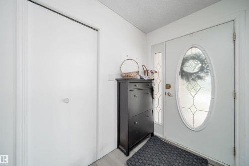 Entryway featuring a white door with an oval leaded glass insert, a coordinating sidelight, and wood-finish flooring - 6403 132 Street, Edmonton, AB - Indoor Photo Showing Other Room