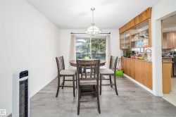 Dining area featuring wood-finish flooring, a built-in display cabinet with glass doors, a large window, a ceiling-mounted light fixture, and an open entryway - 