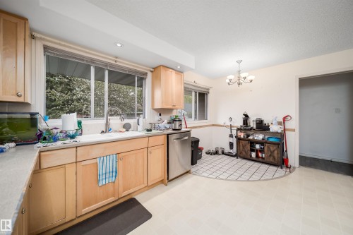 Kitchen featuring light wood cabinetry, a stainless steel dishwasher, and a large window above the sink - 6403 132 Street, Edmonton, AB - Indoor Photo Showing Kitchen