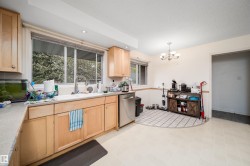 Kitchen featuring light wood cabinetry, a stainless steel dishwasher, and a large window above the sink - 