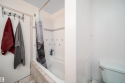 White tiled shower surround with decorative accent tiles and a built-in tub - 