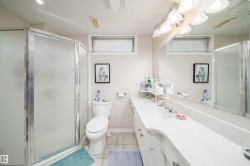 Bathroom featuring a white vanity with integrated sink, a large wall mirror, and a shower enclosure with frosted glass panels - 