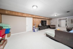 Finished basement living area featuring wood paneling accents, recessed ceiling lighting, and soft carpeting - 