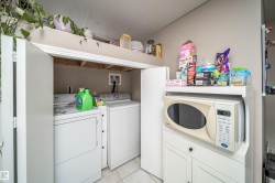 Laundry closet with bi-fold doors, white ceramic tile flooring, and overhead storage - 