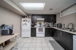 Kitchen featuring dark wood-finish cabinetry, light-toned countertops, and white square tile flooring - 